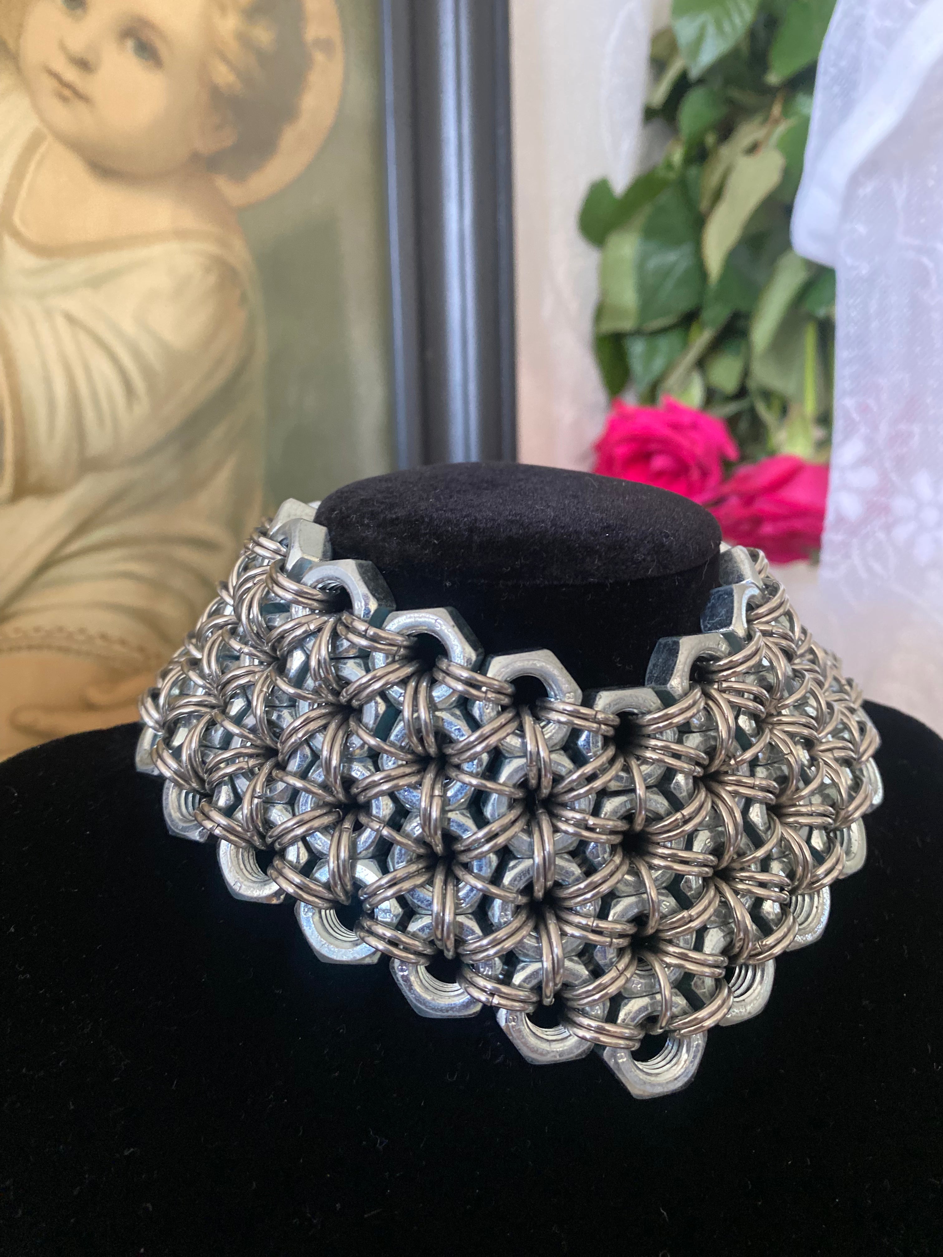 Close-up photo of a metal choker necklace made from stainless steel screws and chainmail for an ultimate shine; a sustainable, handmade product from Berlin.