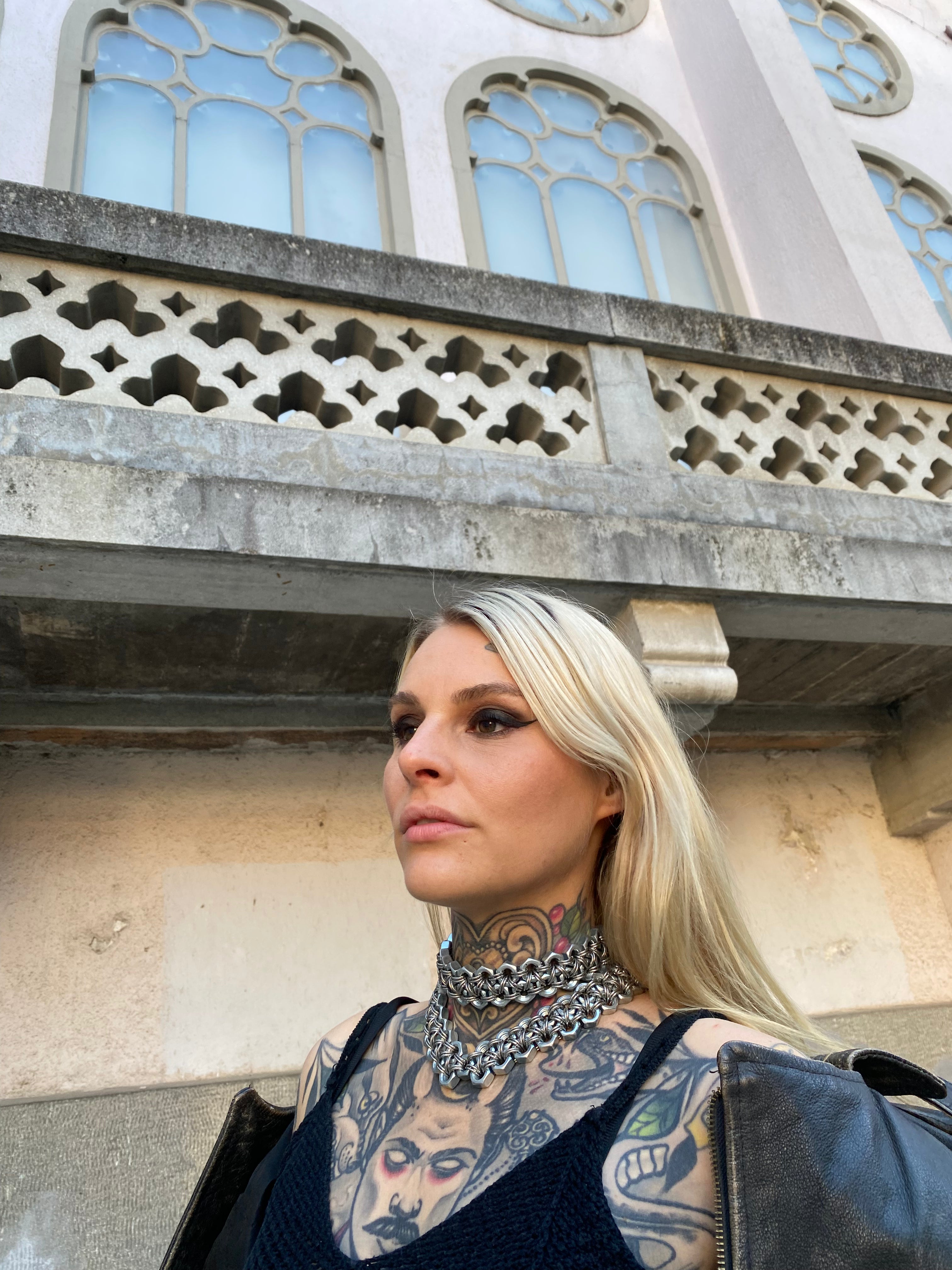Model wearing a heavy-duty choker made from stainless steel chainmail and industrial screws, creating a bold, avant-garde statement piece for a heavy alternative fashion look.