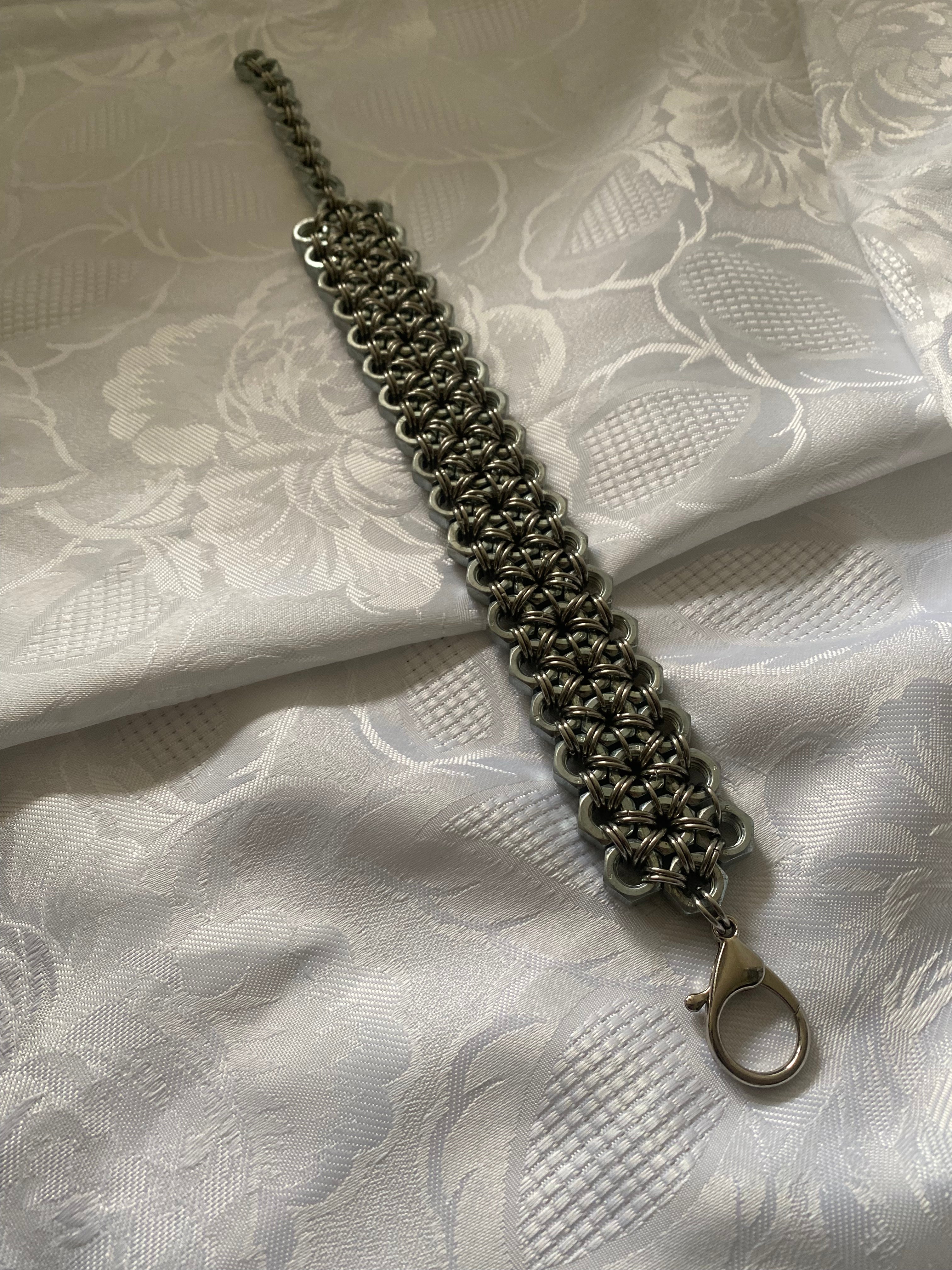 Heavy-duty chainmail-inspired choker necklace on white lace, made from stainless steel screws and chainmail, perfect for fans of gothic, alternative, and industrial fashion.