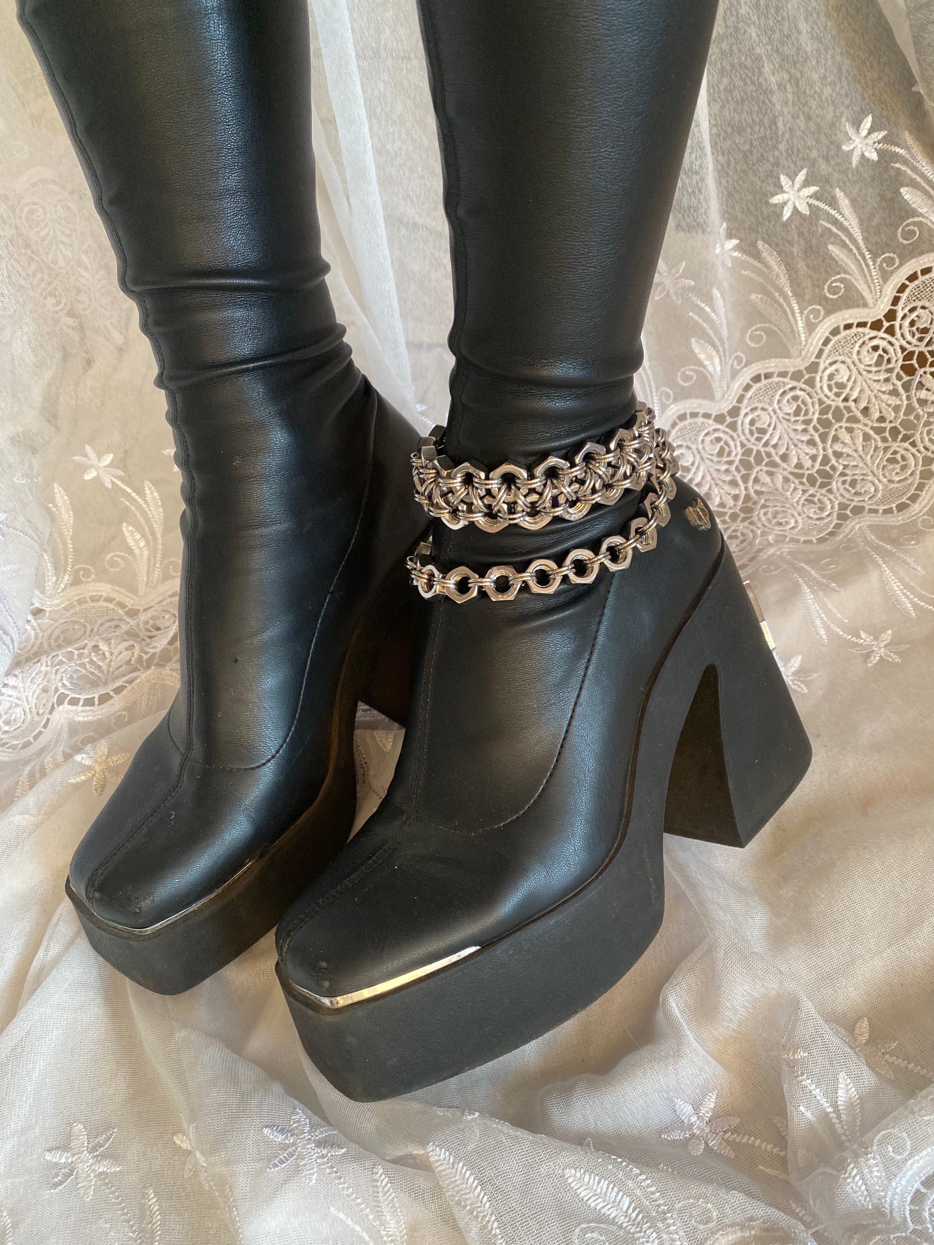 Handmade stainless steel chainmail chain displayed on a Naked Wolfe boot as a boot charm. Shiny industrial statement piece made in Berlin, shown in a gothic setting with white lace.