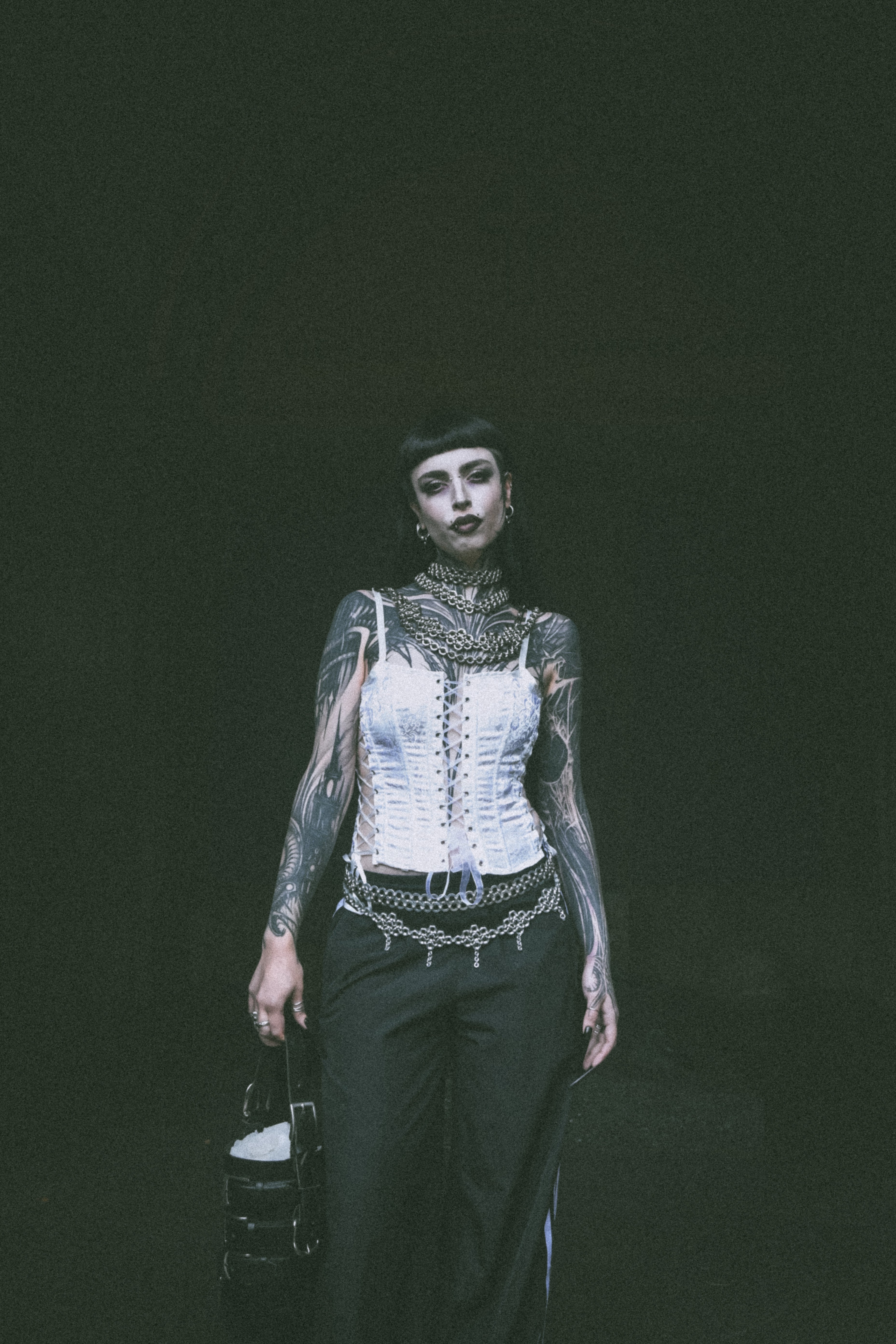 An alternative model wears unique chainmail necklaces and belts made from genuine screws and rings for an industrial fashion look, and carries a repurposed leather handbag.