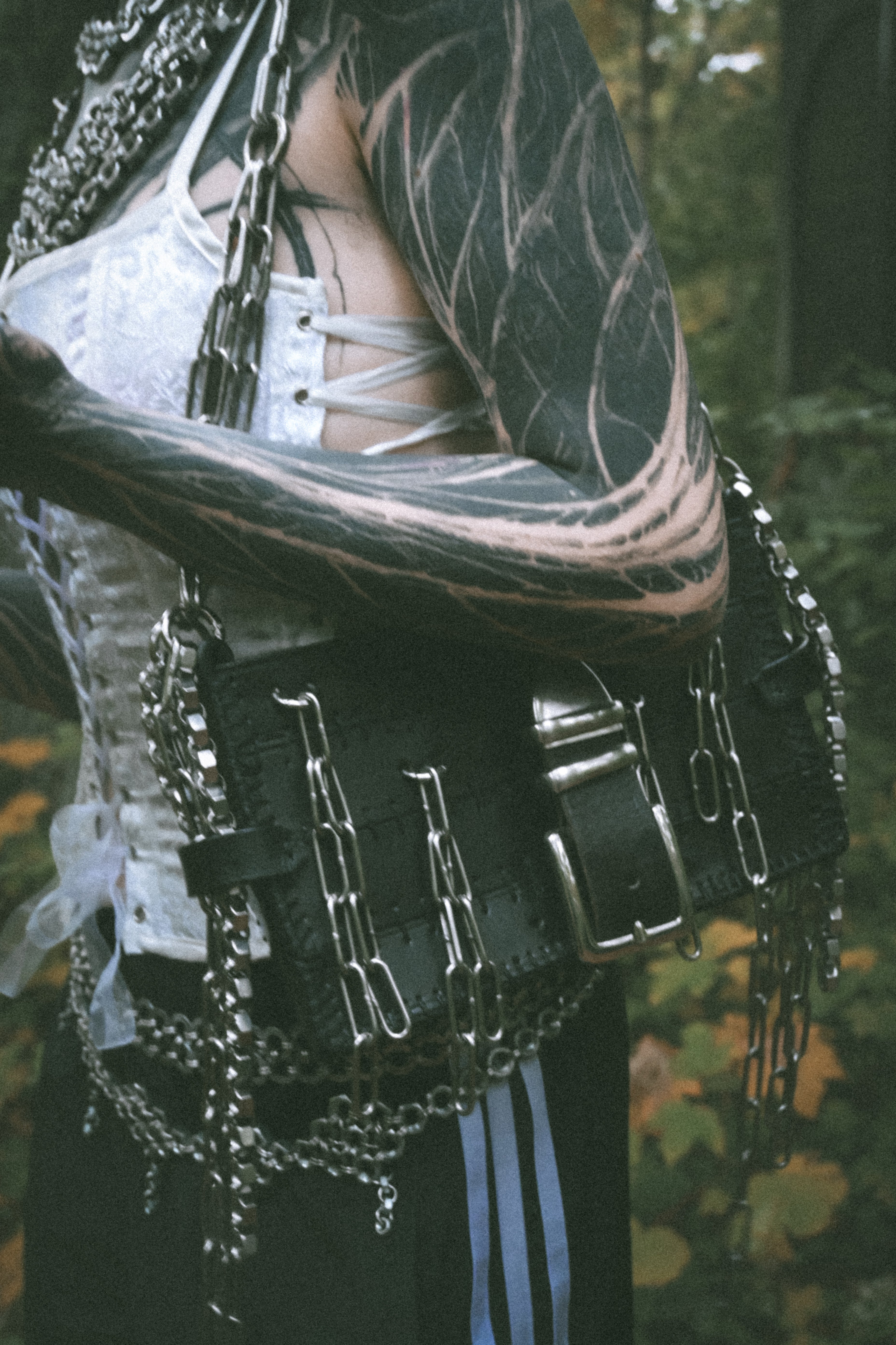 Alternative vampire-inspired model wearing a handmade shoulder bag made from repurposed leather with unique industrial chainmail details, photographed in an actual gothic graveyard.