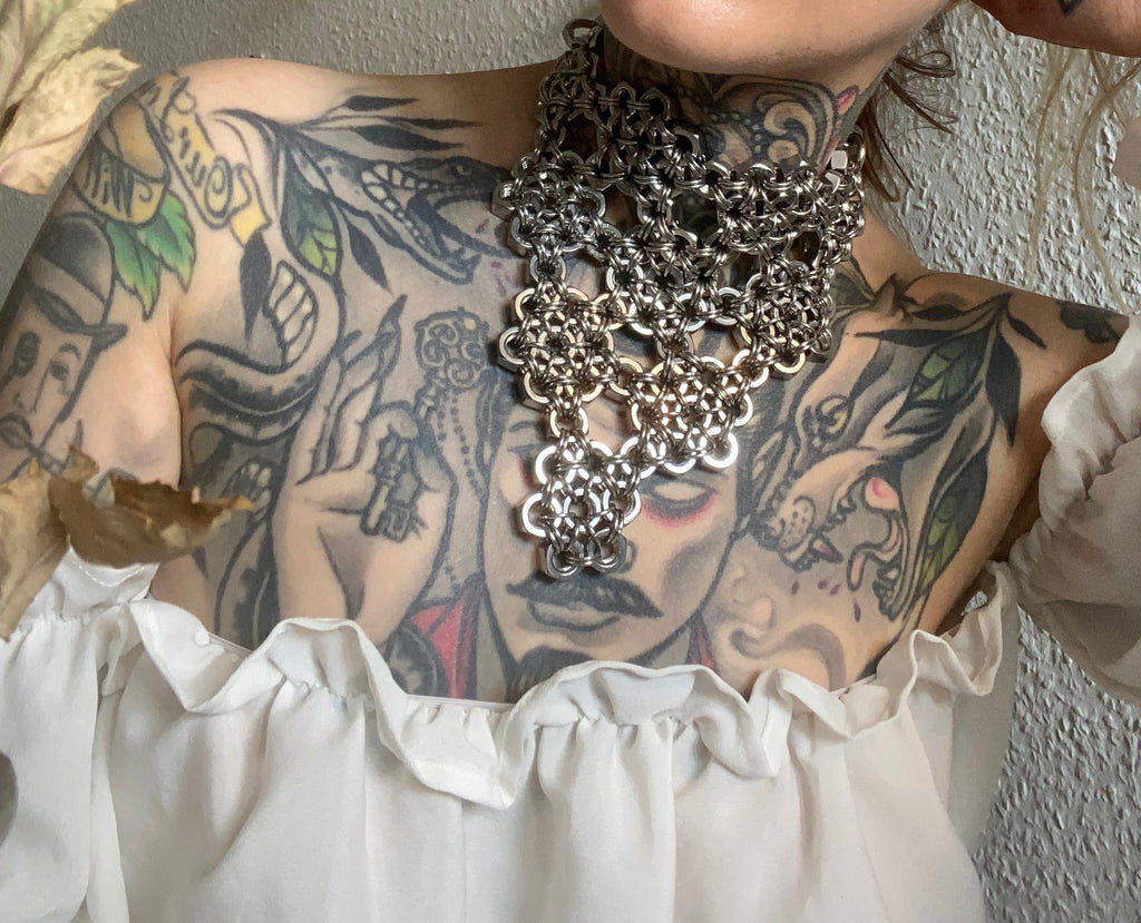 Close-up of a handcrafted floral chainmail necklace in shiny silver, made from stainless steel rings and screws for an industrial vibe, created in Berlin.