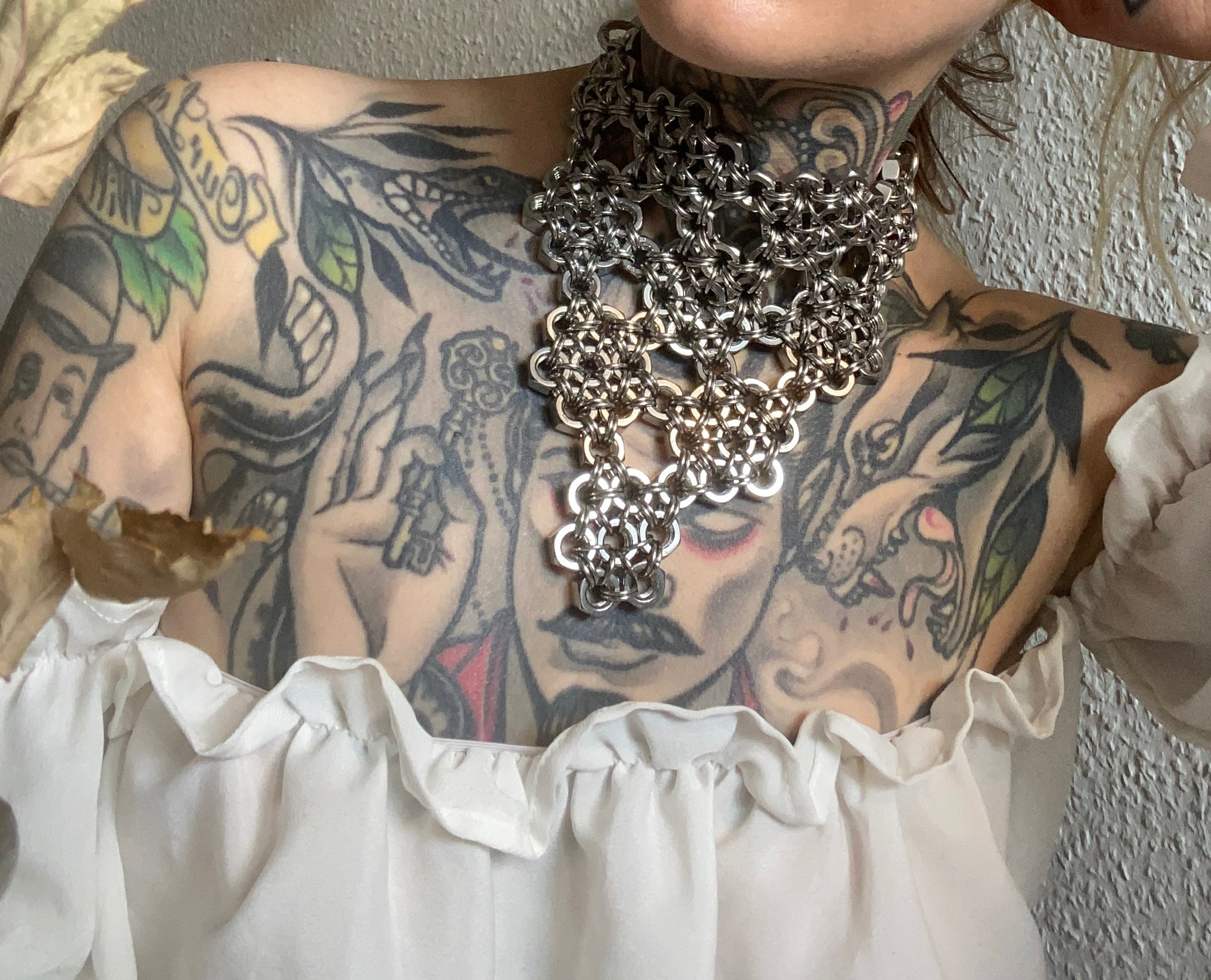 Close-up of a handcrafted floral chainmail necklace in shiny silver, made from stainless steel rings and screws for an industrial vibe, created in Berlin.