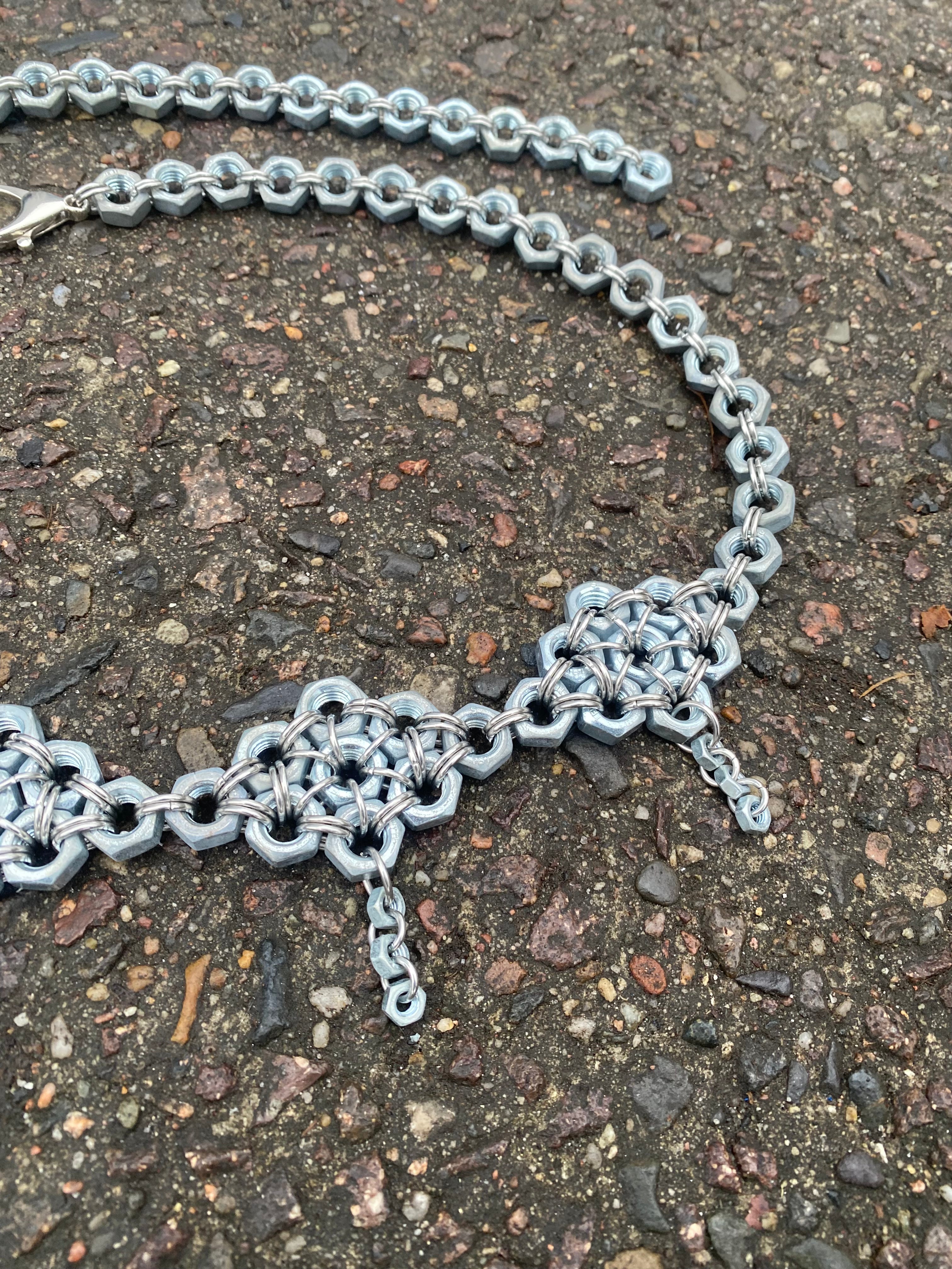 close up Unique handmade chainmail belt made from stainless steel rings and genuine screws, displayed in the photo. Crafted in Berlin, inspired by techno and alternative fashion.