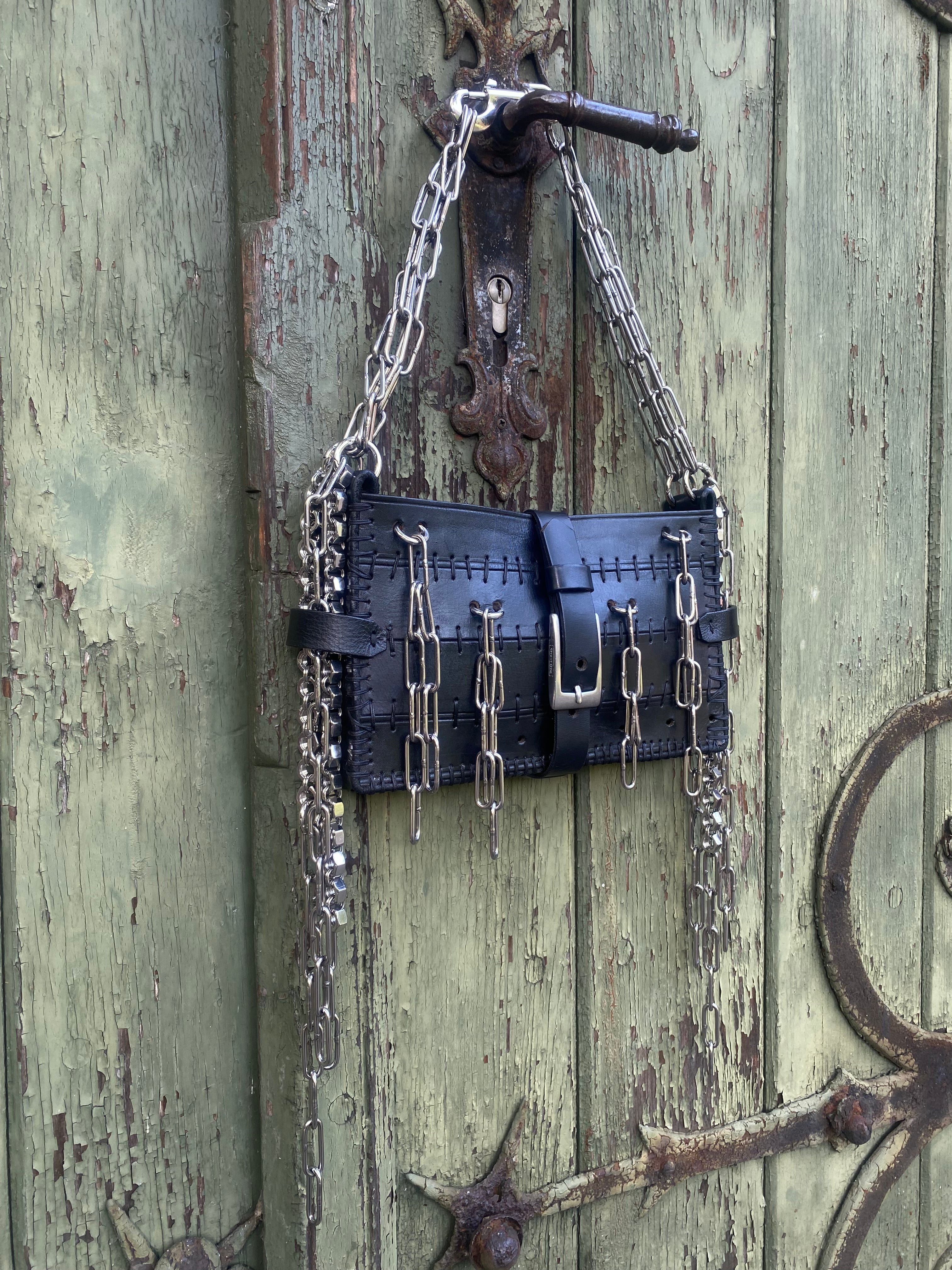 Shoulder bag with unique industrial chainmail details hanging on a vintage door. Alternative fashion, techno fashion, and luxury accessories made in Berlin.