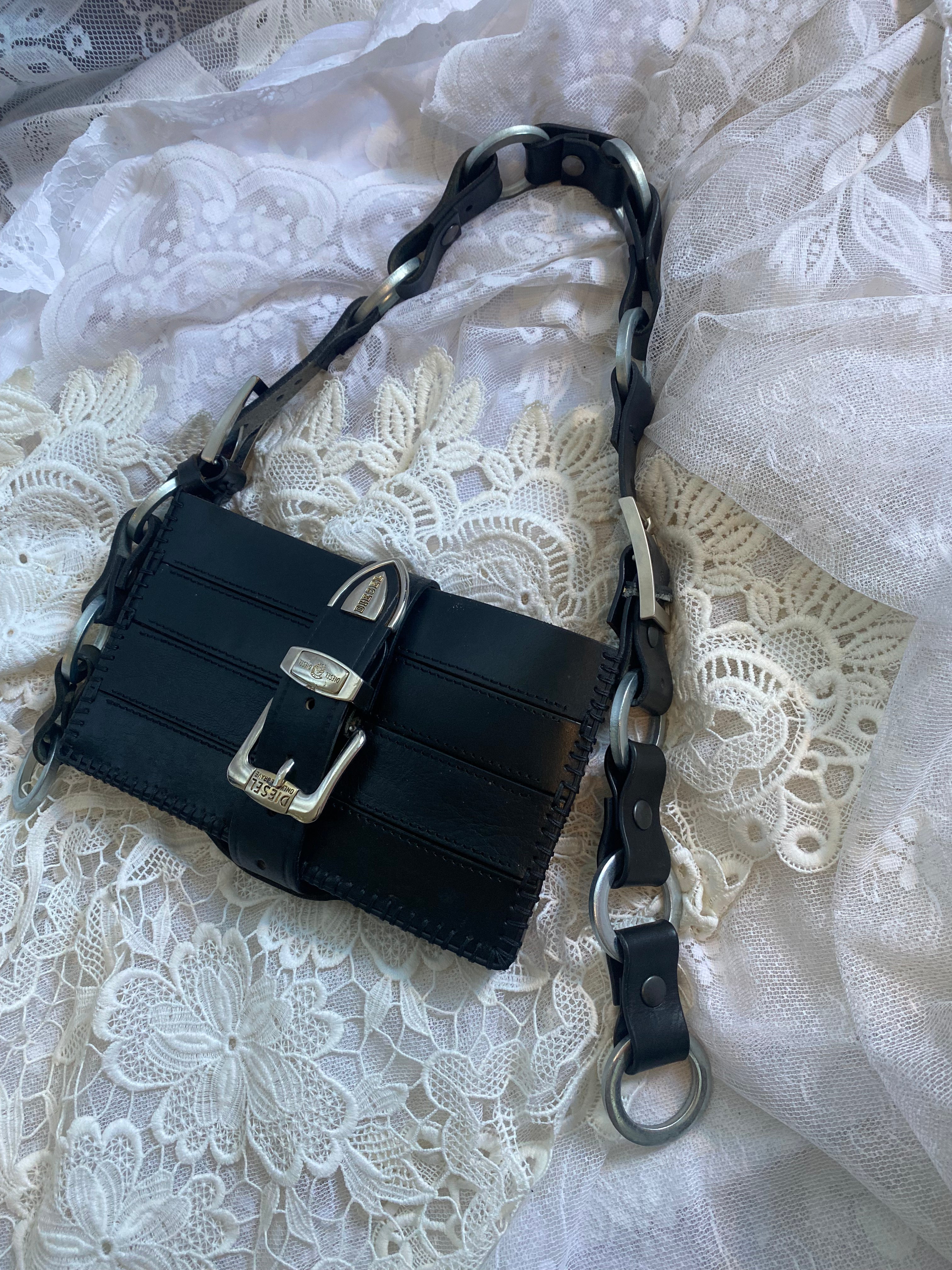 Handmade black leather handbag on Victorian gothic white lace, featuring a handle of genuine screw rings sewn with leather for an industrial Berlin fashion look. A high-quality accessory with durable material and luxury craftsmanship.