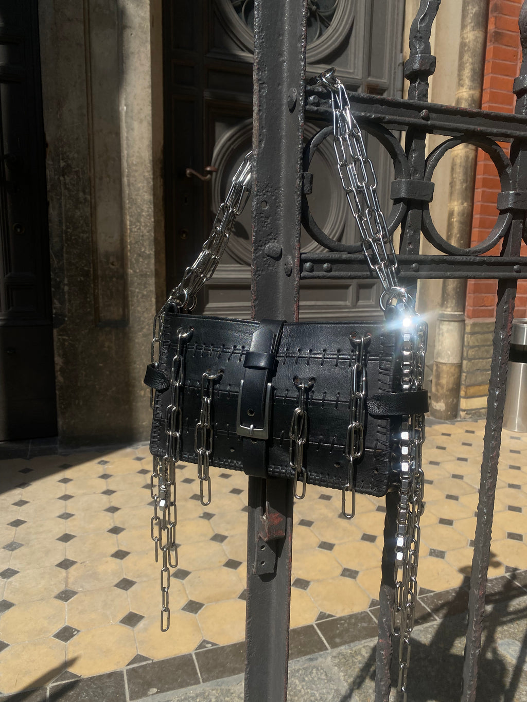 Luxury-quality handmade handbag crafted from upcycled leather, hanging on a fence. Alternative fashion made in Berlin, the capital of style.